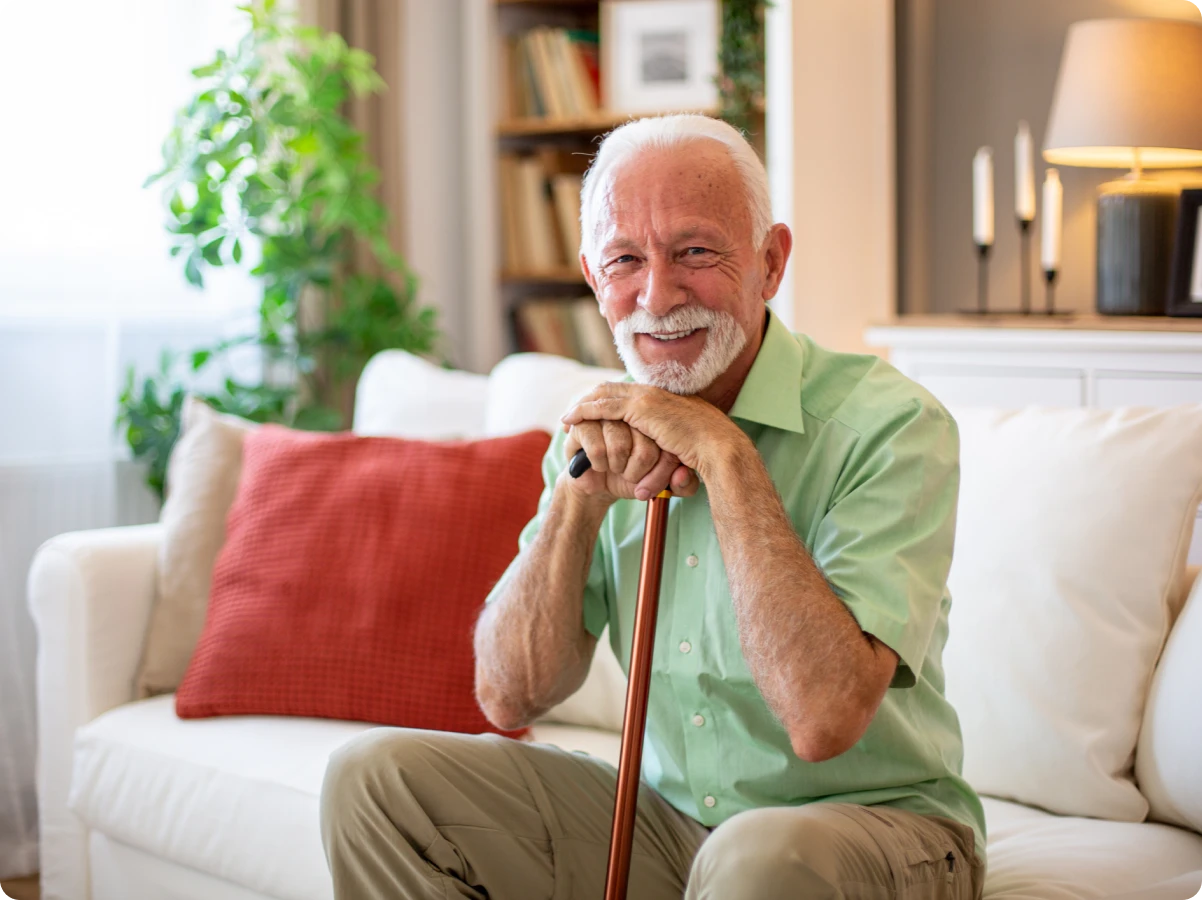 Elderly man smiling with cane at home